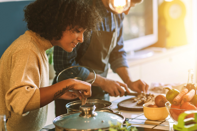 A couple cooking in a kitchen, preparing a meal together.
