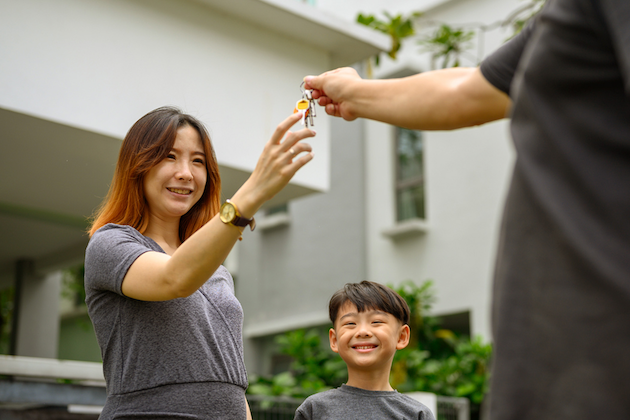 A woman and child smiling while she receives a set of keys.